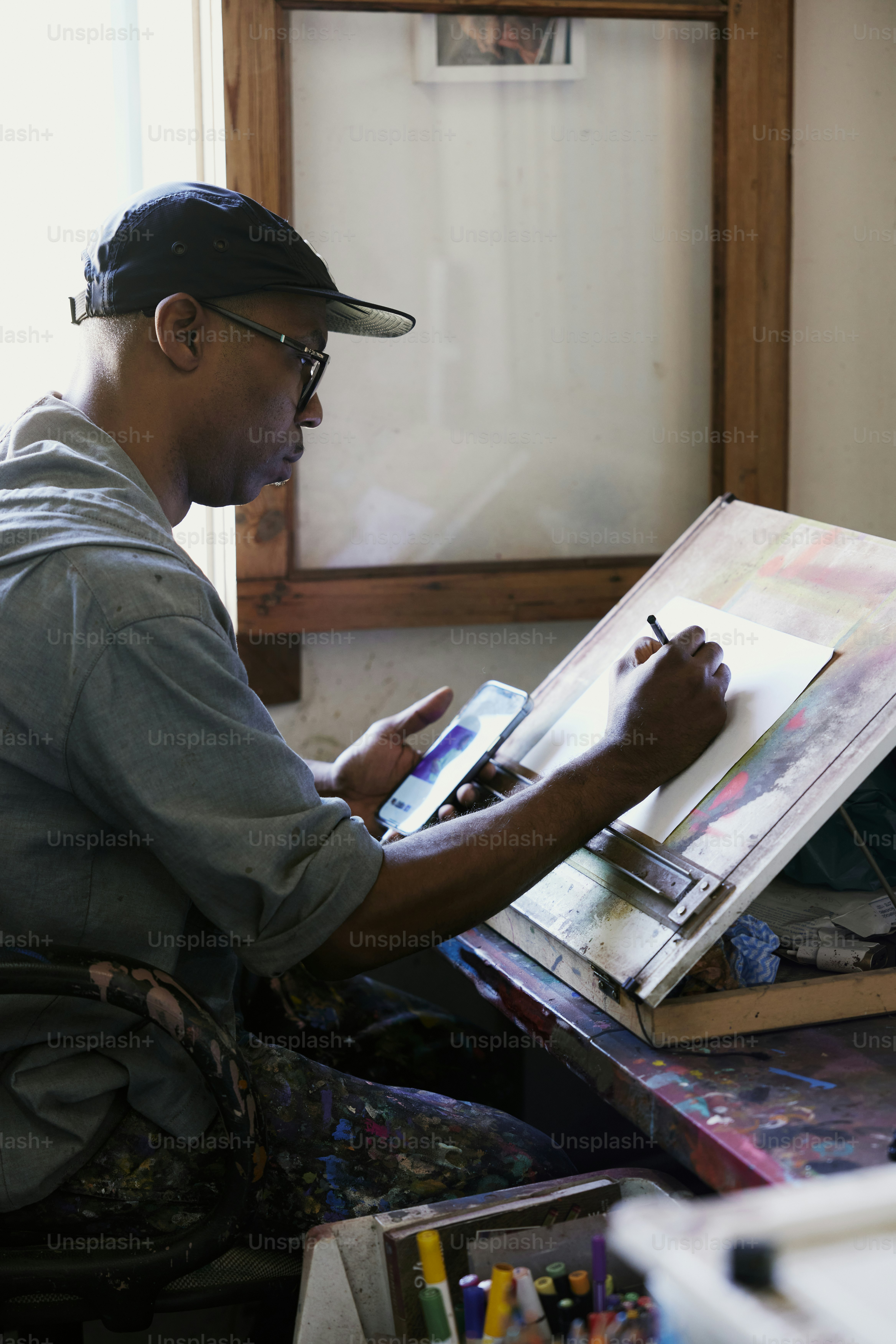 Un homme assis devant un tableau sur un chevalet