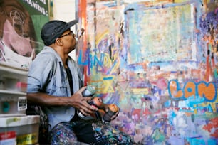 Un uomo che dipinge un muro con vernice spray