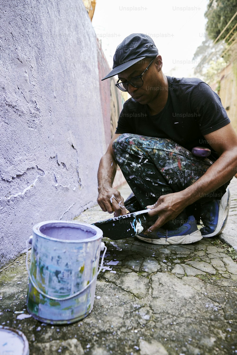 a man sitting on the ground painting a wall