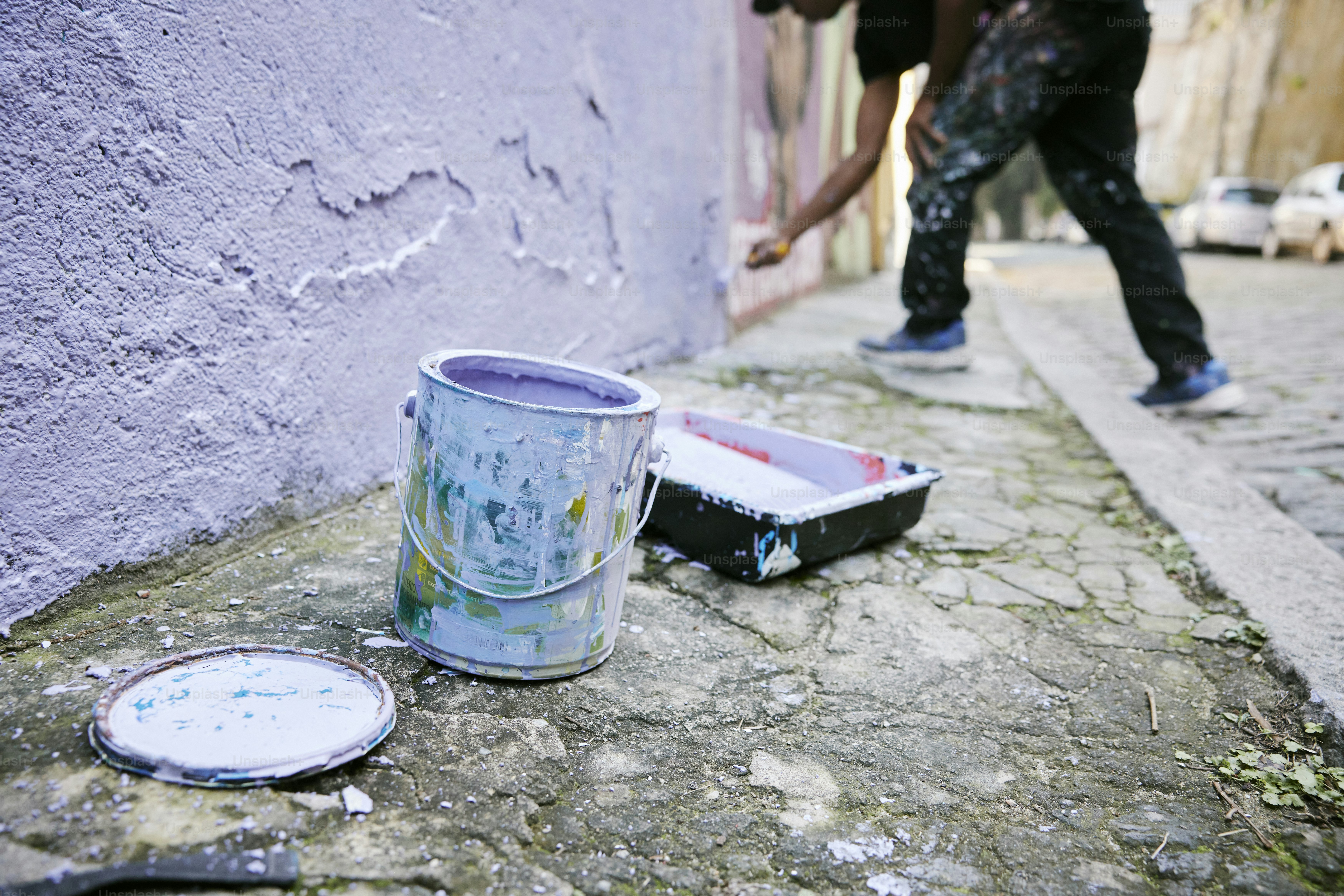 eine Dose Farbe, die neben einem Pinsel auf dem Boden sitzt