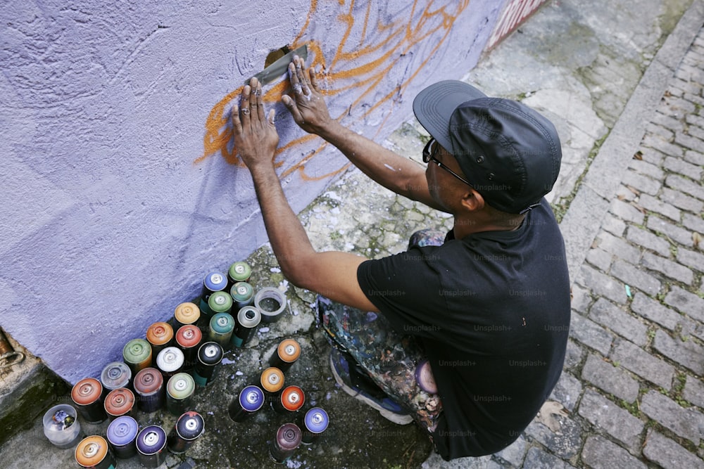 a man is painting a wall with cans of paint