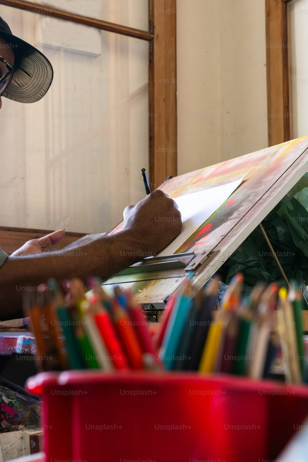 Un uomo con un cappello dipinge con matite colorate