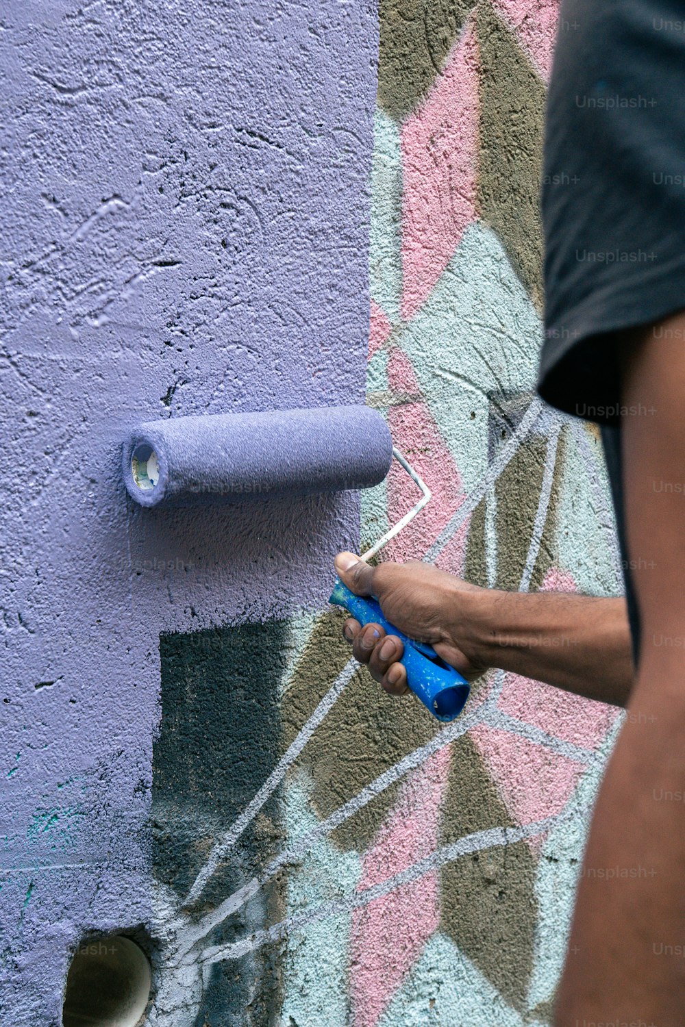 eine Person, die eine Farbrolle benutzt, um eine Wand zu streichen