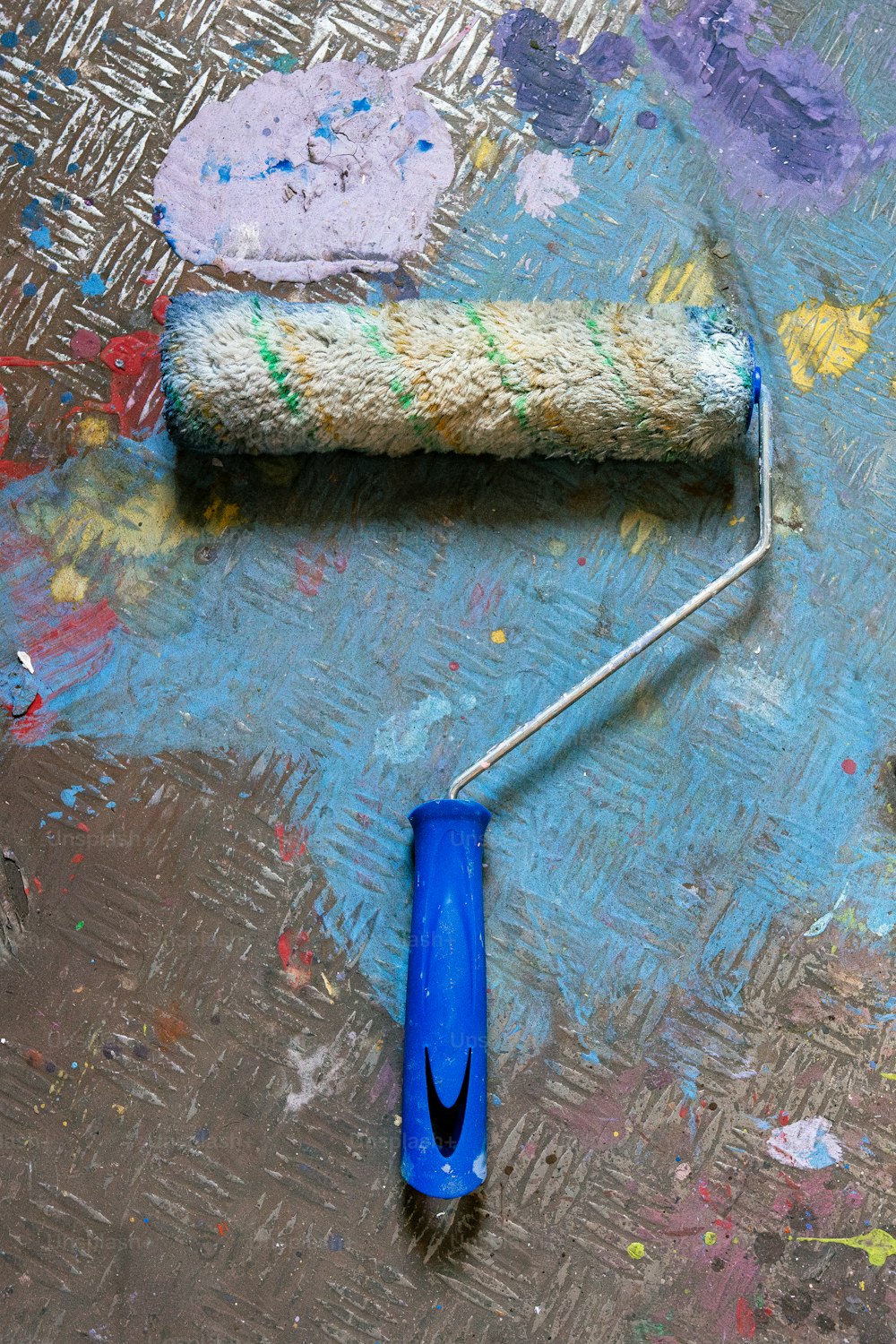 a blue paint roller laying on top of a dirty floor