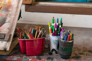 Un par de tazas llenas de muchos lápices de colores