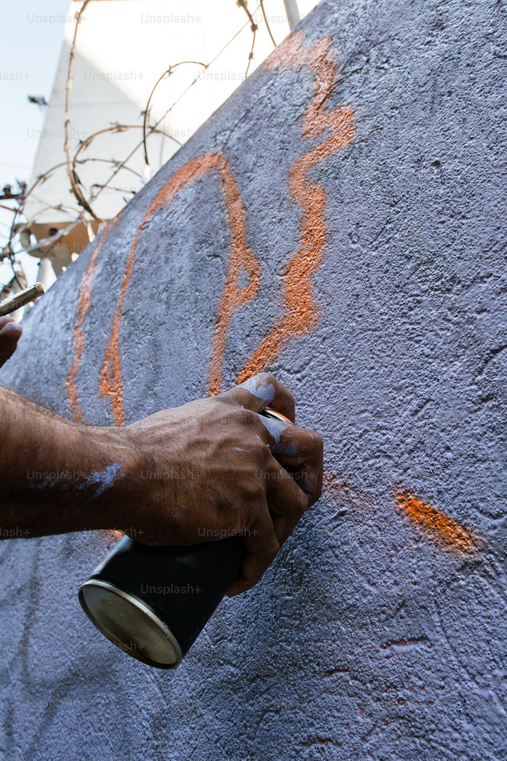 a man painting a wall with orange paint