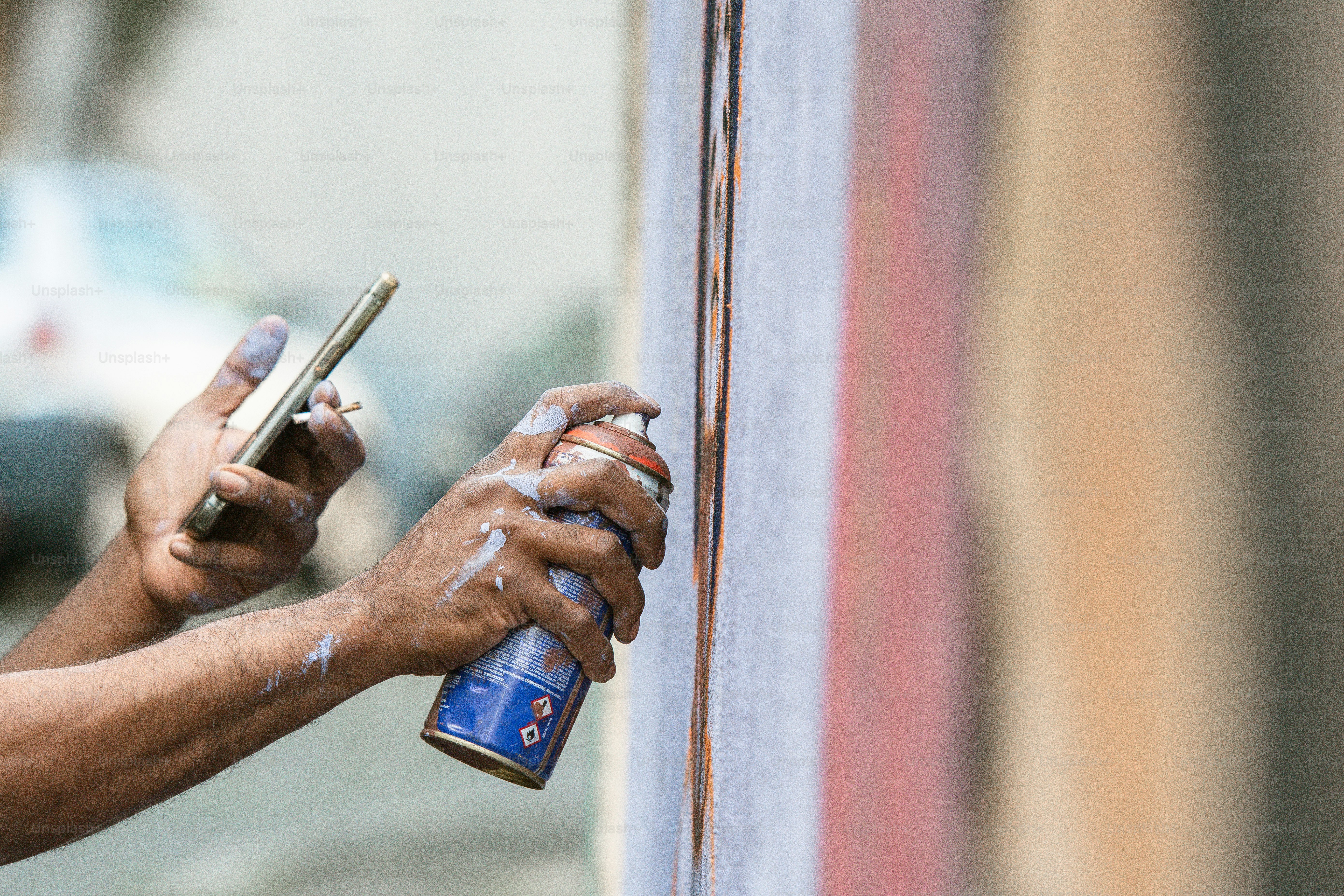 eine Person, die eine Sprühflasche und ein Mobiltelefon hält