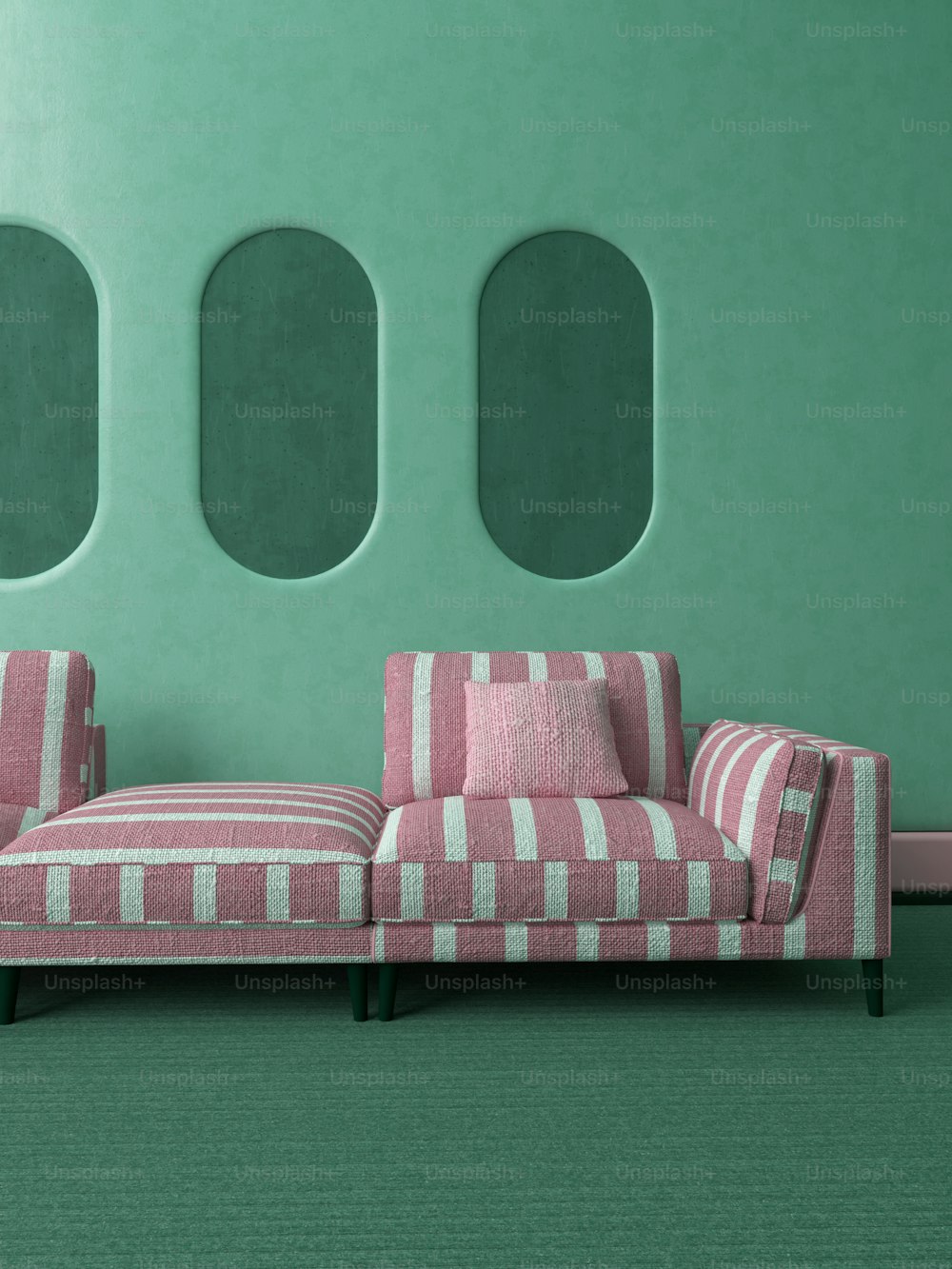 a pink and white couch sitting in front of a green wall