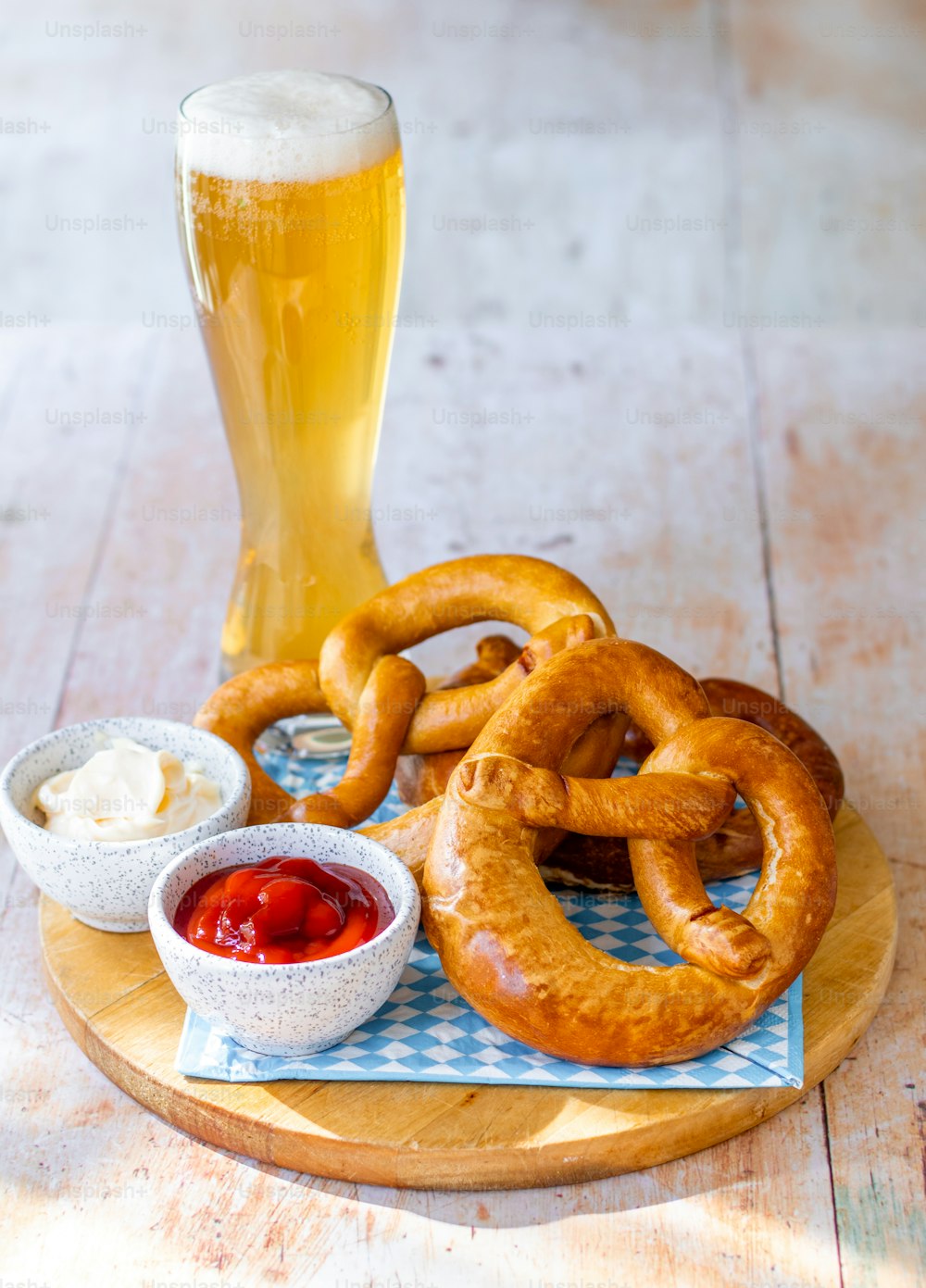 uma bandeja de madeira coberta com pretzels ao lado de um copo de cerveja