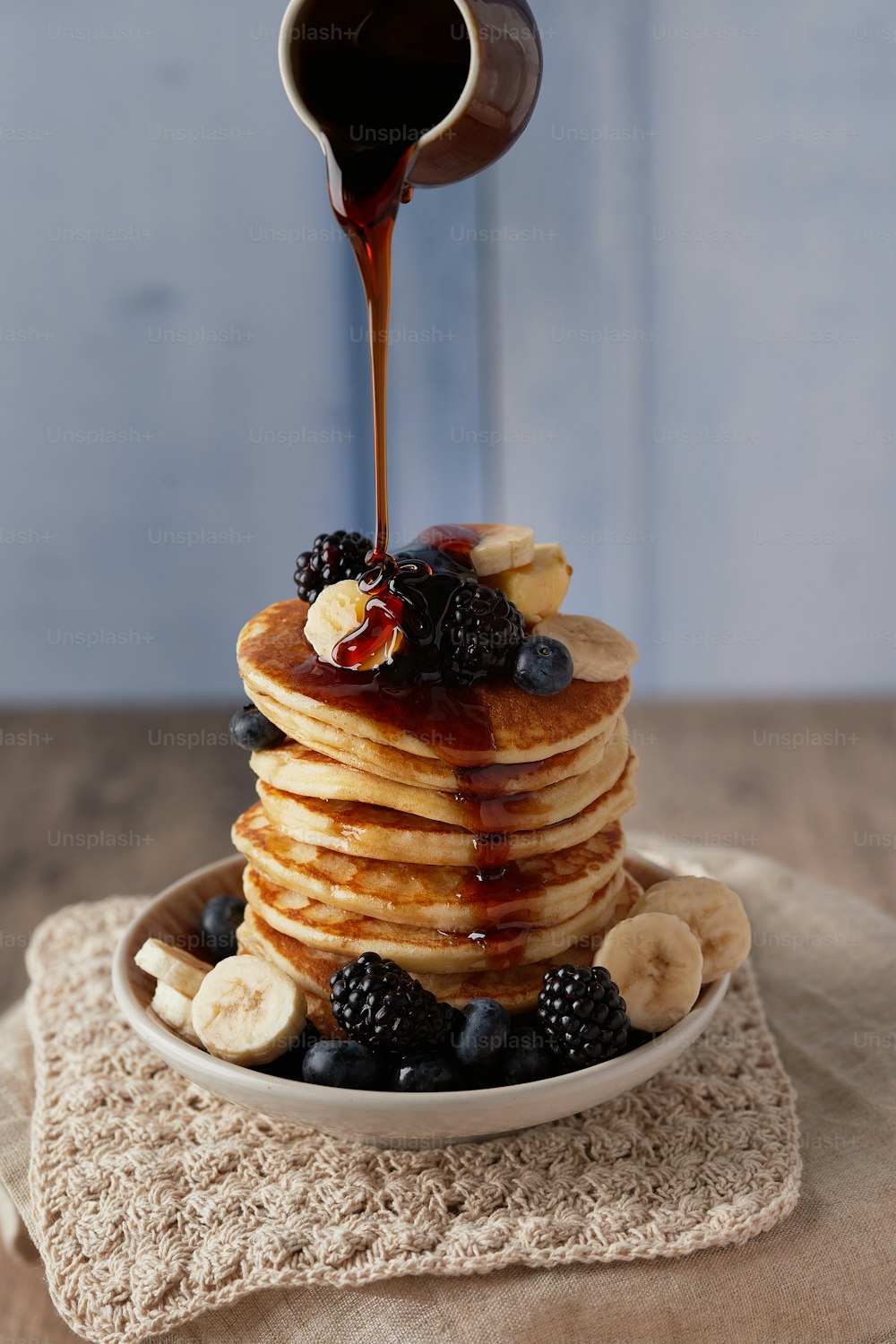 a stack of pancakes with syrup being poured on top