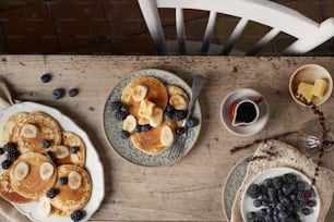 uma mesa coberta com panquecas e frutas ao lado de uma xícara de café