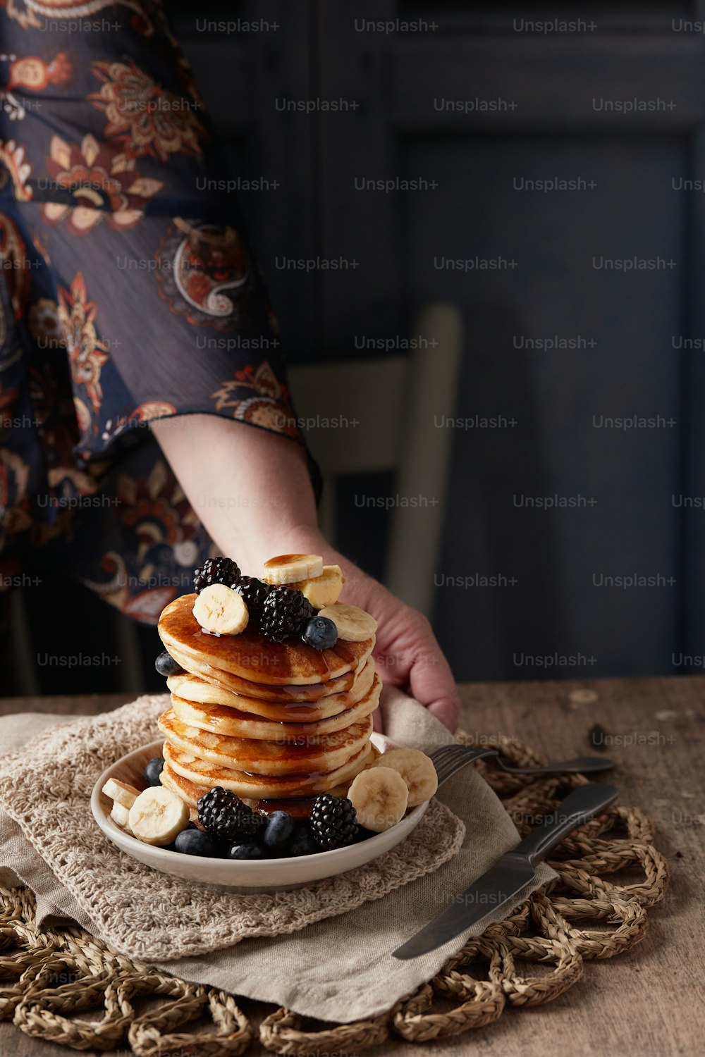 a stack of pancakes topped with bananas and blackberries
