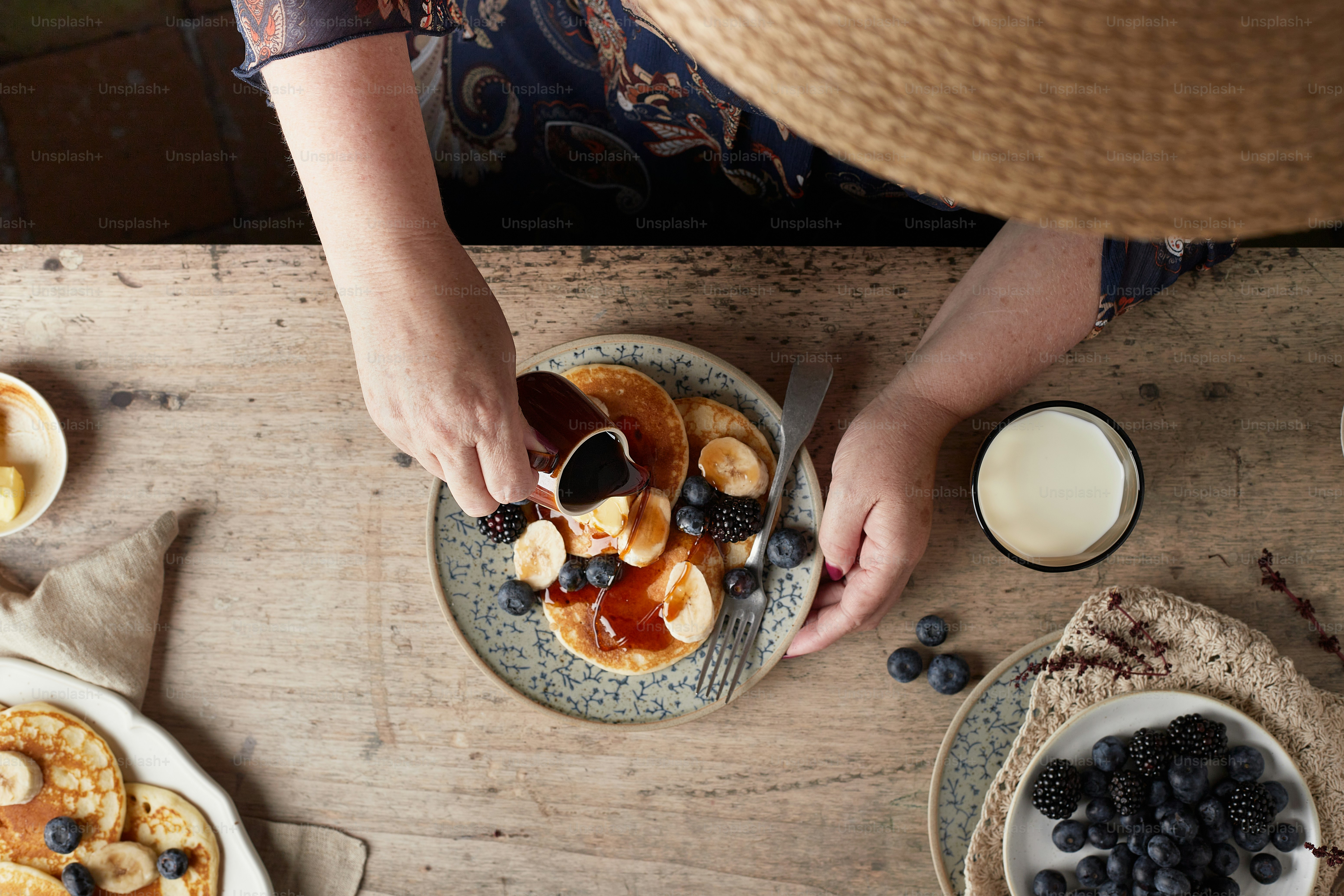 Una persona está poniendo jarabe en un plato de panqueques