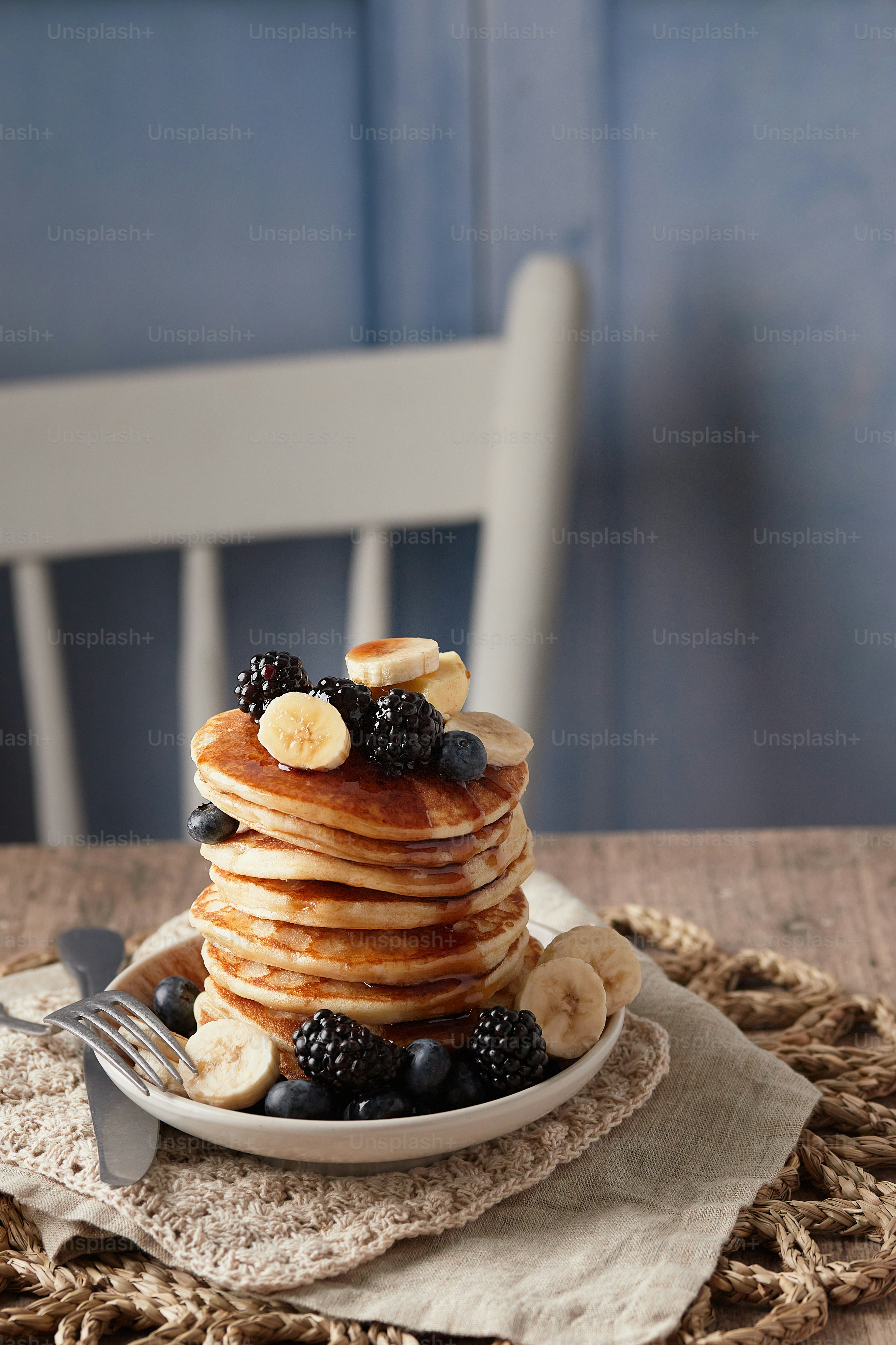 a stack of pancakes topped with bananas and blackberries