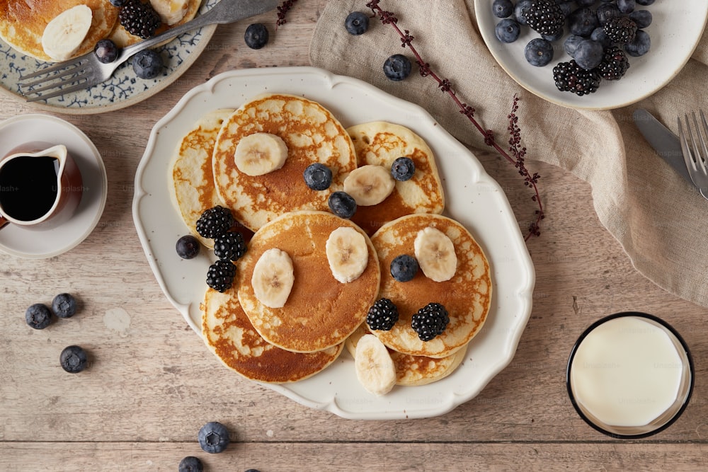 pancakes with bananas and blueberries on a white plate