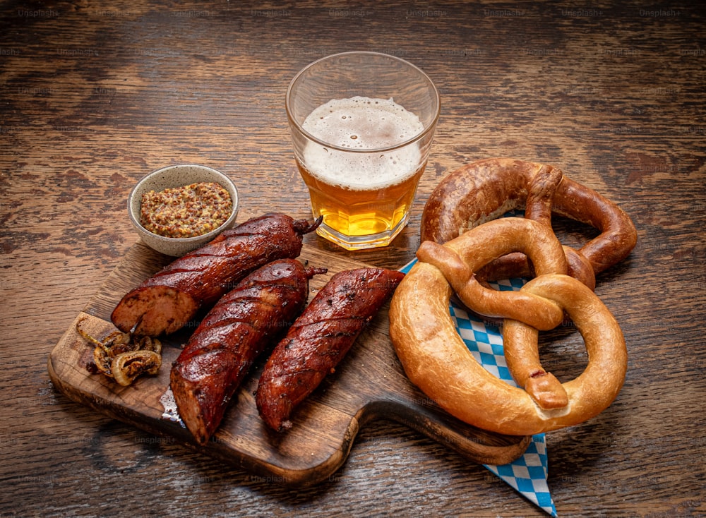 a wooden table topped with sausages and pretzels