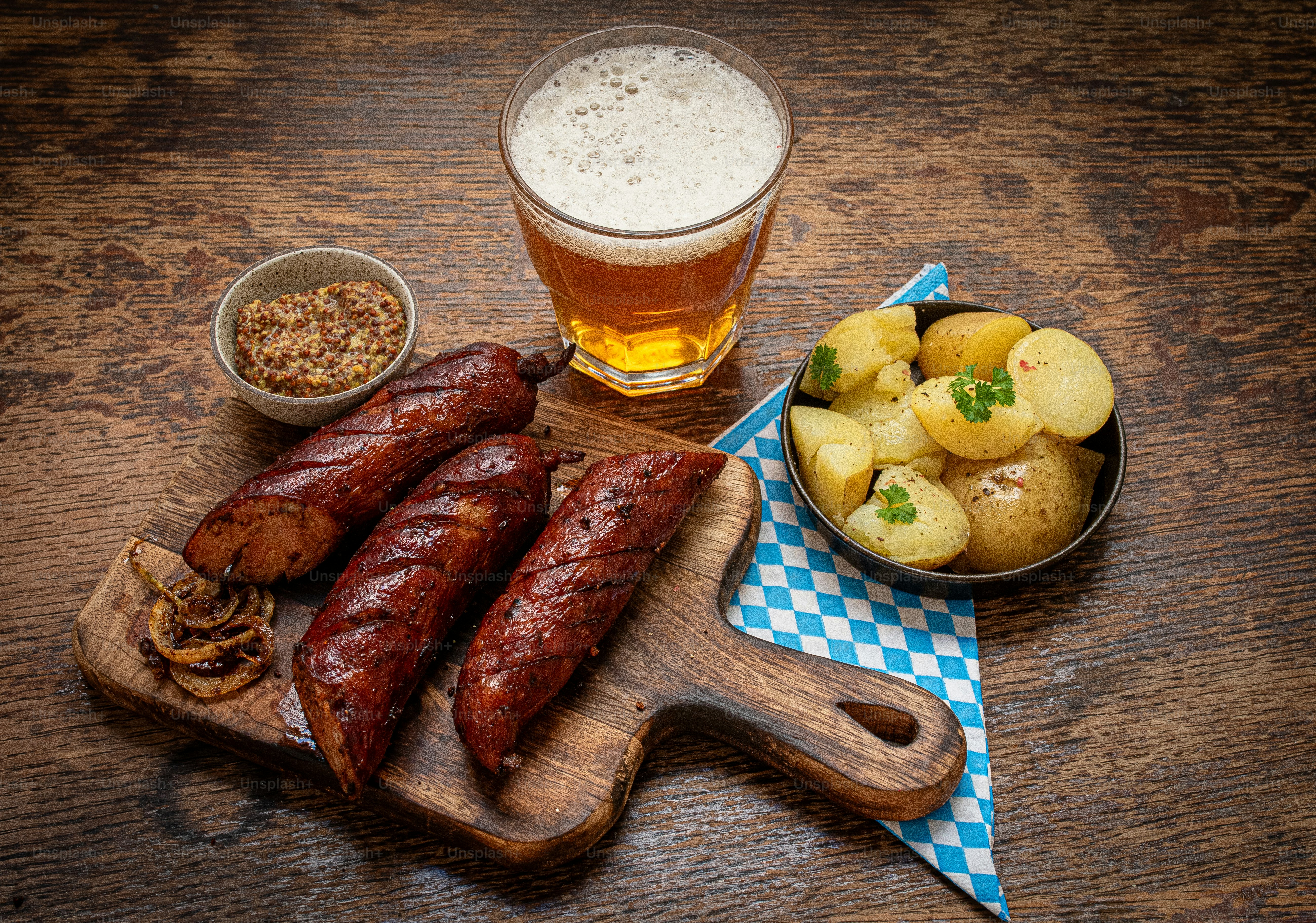 a wooden cutting board topped with sausages and potatoes