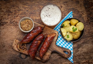 a wooden cutting board topped with sausages and potatoes