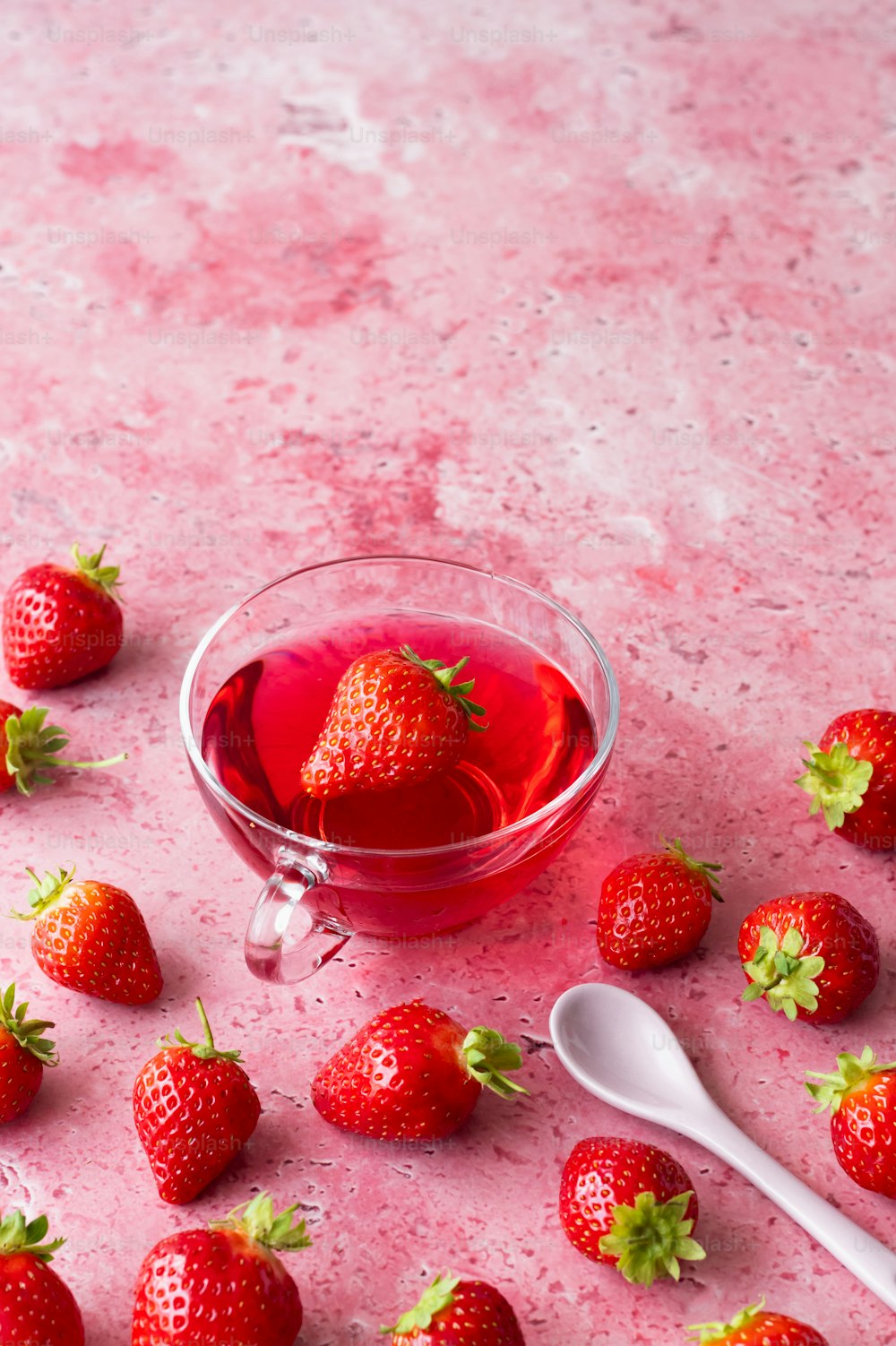 a bowl of strawberries next to a glass of liquid