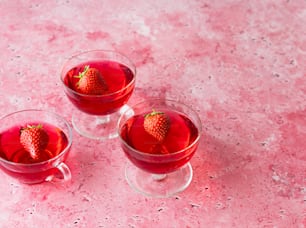 Drei Gläser rote Flüssigkeit mit einer Erdbeere oben drauf