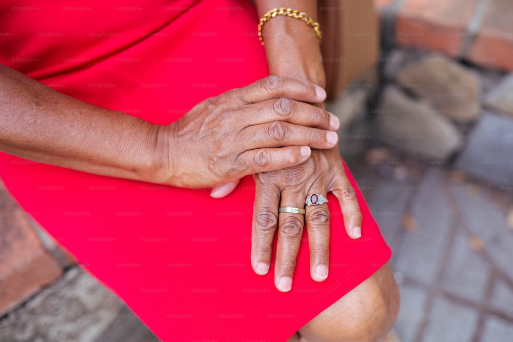 uma mulher em um vestido vermelho segurando suas mãos juntas