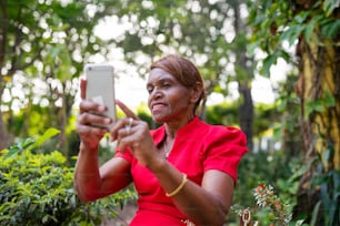 Una mujer con un vestido rojo tomando una foto con un teléfono celular