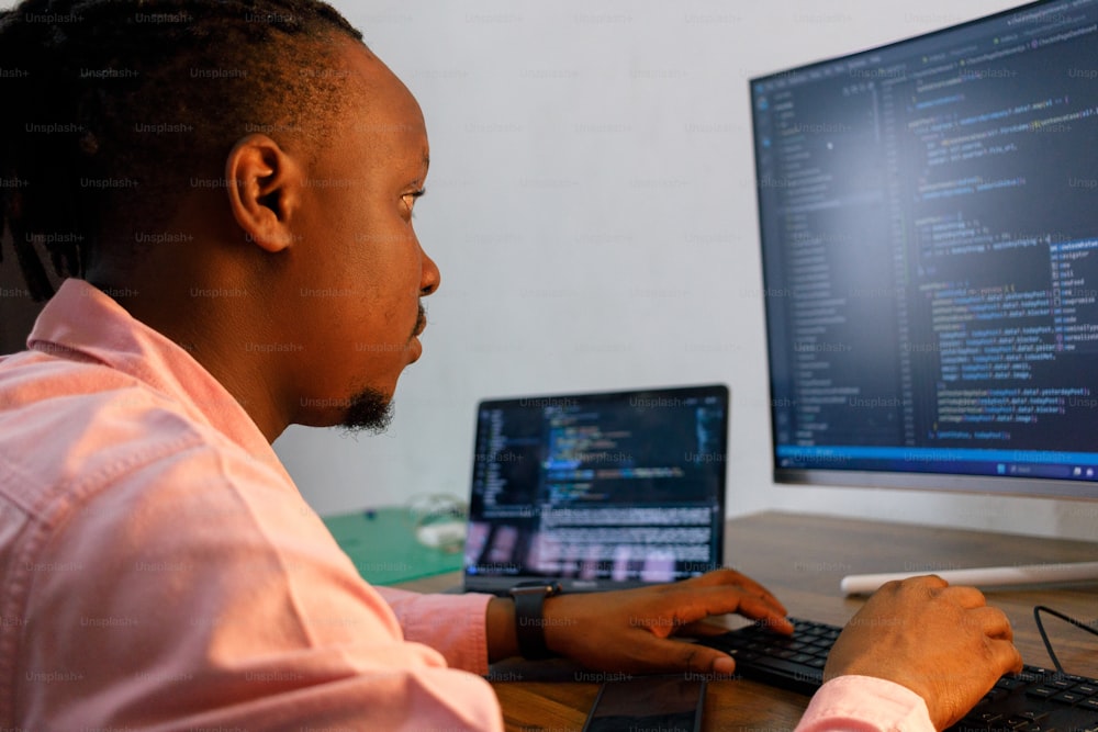 a man sitting at a desk using a laptop computer