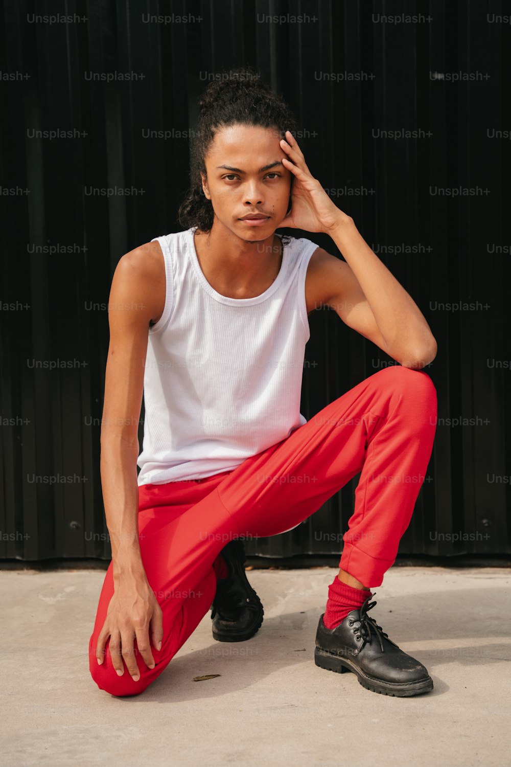 a man sitting on the ground wearing red pants