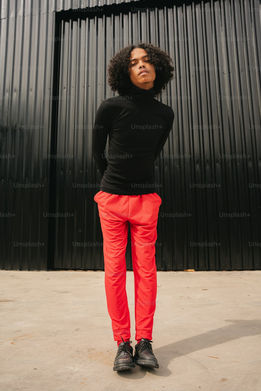 Una mujer con camisa negra y pantalones rojos