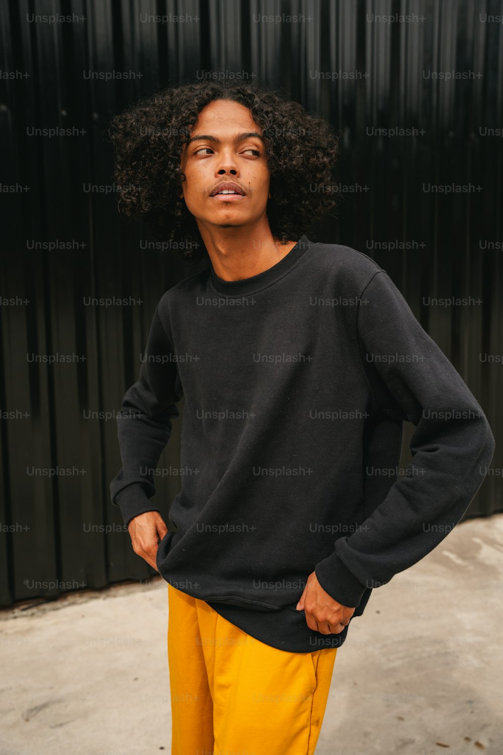 a young man standing in front of a black wall