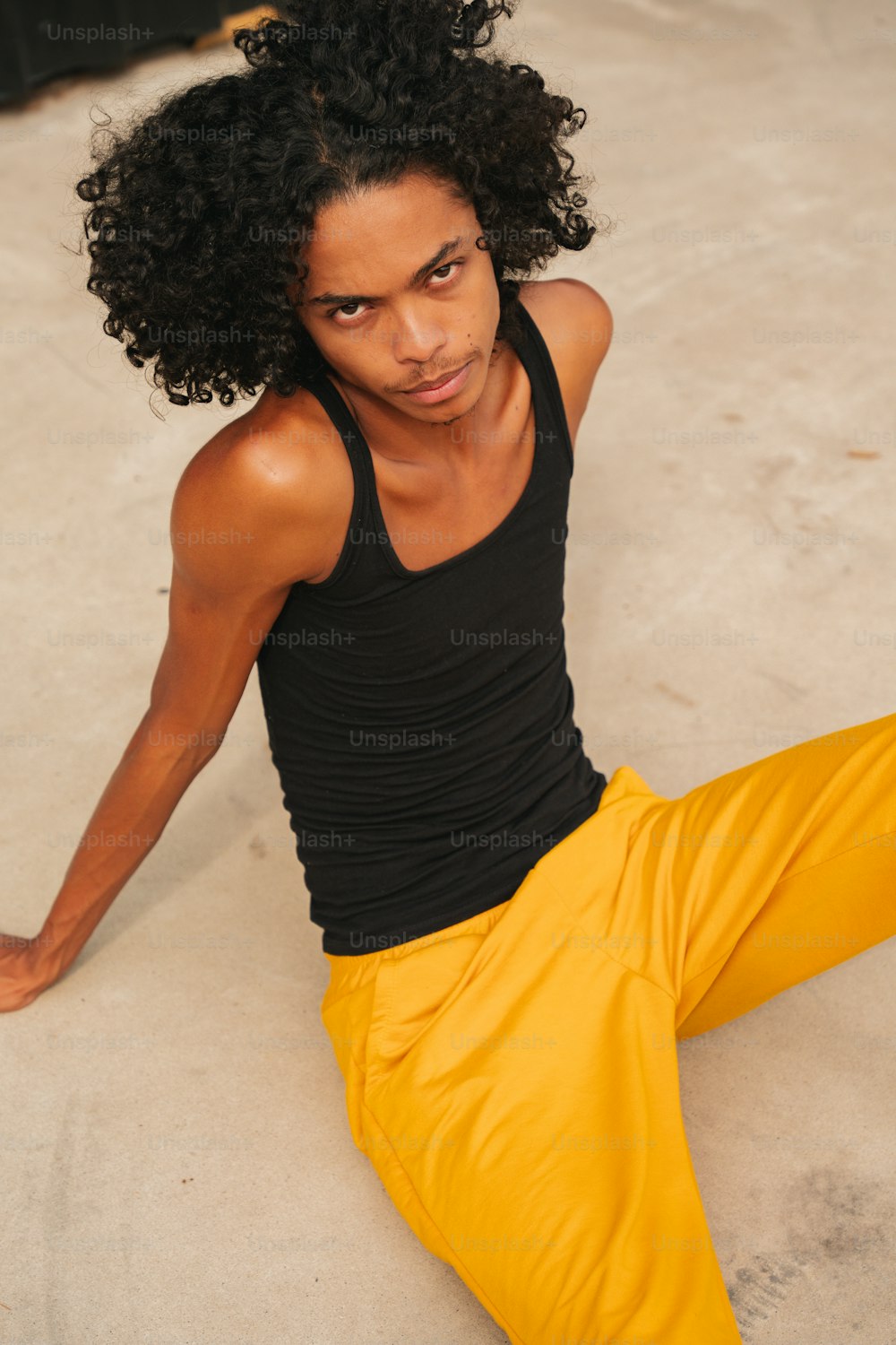 a man sitting on the ground wearing yellow pants