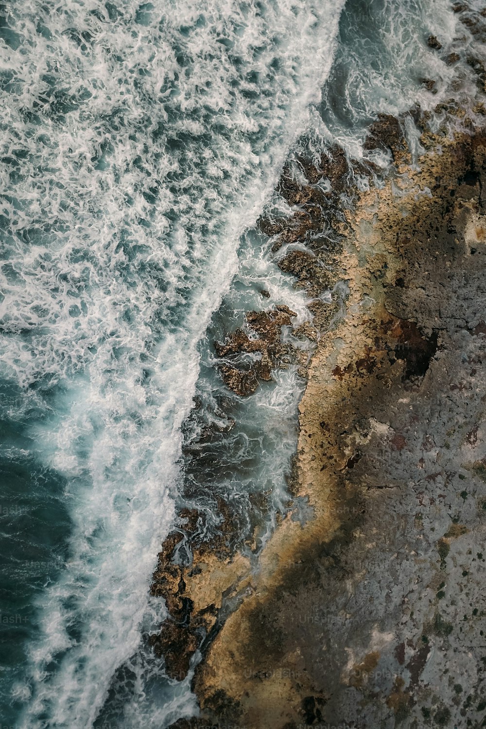 an aerial view of the ocean with waves crashing on the shore