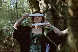 Una donna in piedi nel bosco con in mano due frisbee bianchi