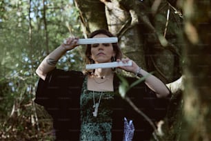 a woman standing in the woods holding two white frisbees