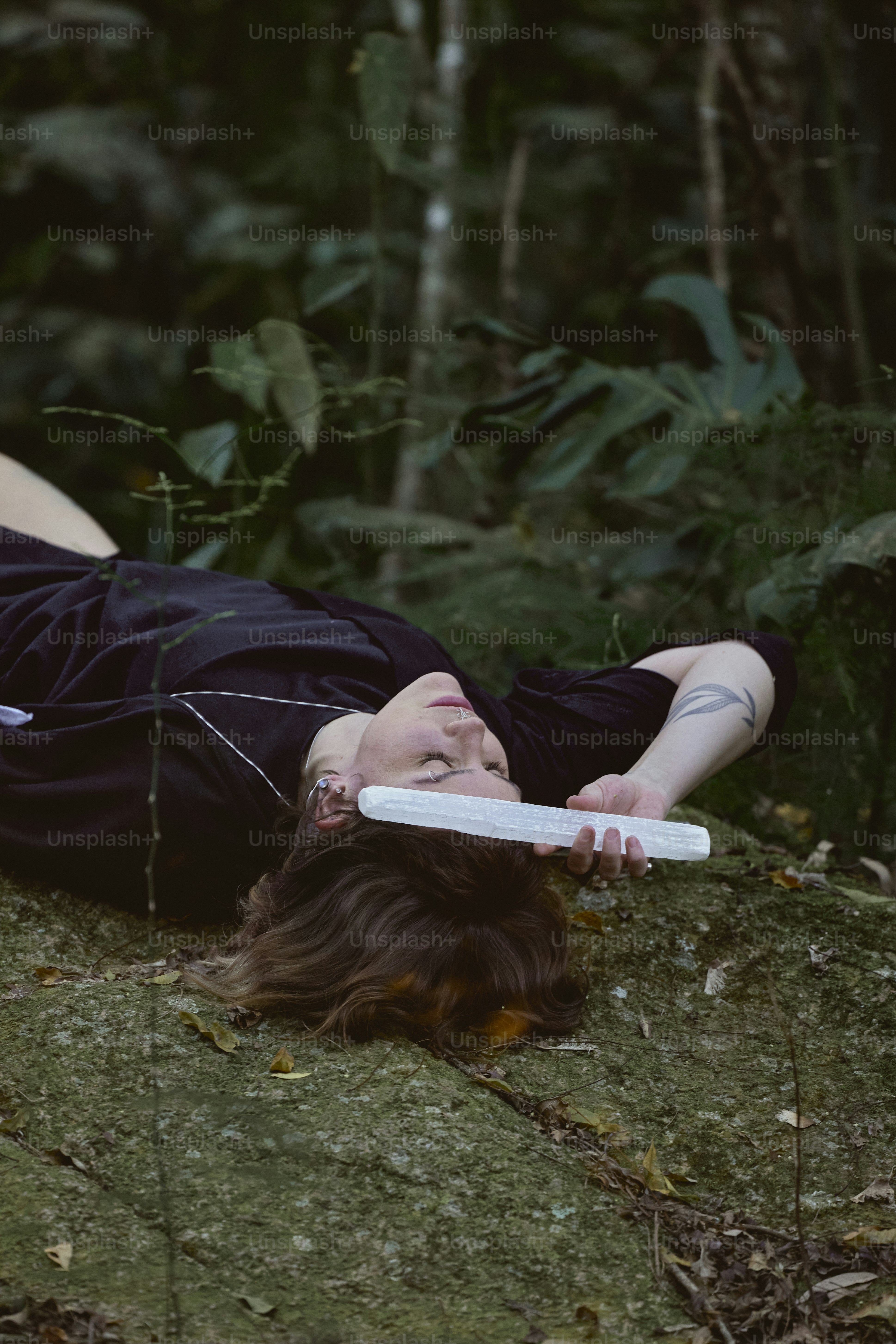 a woman laying on the ground with a frisbee in her mouth
