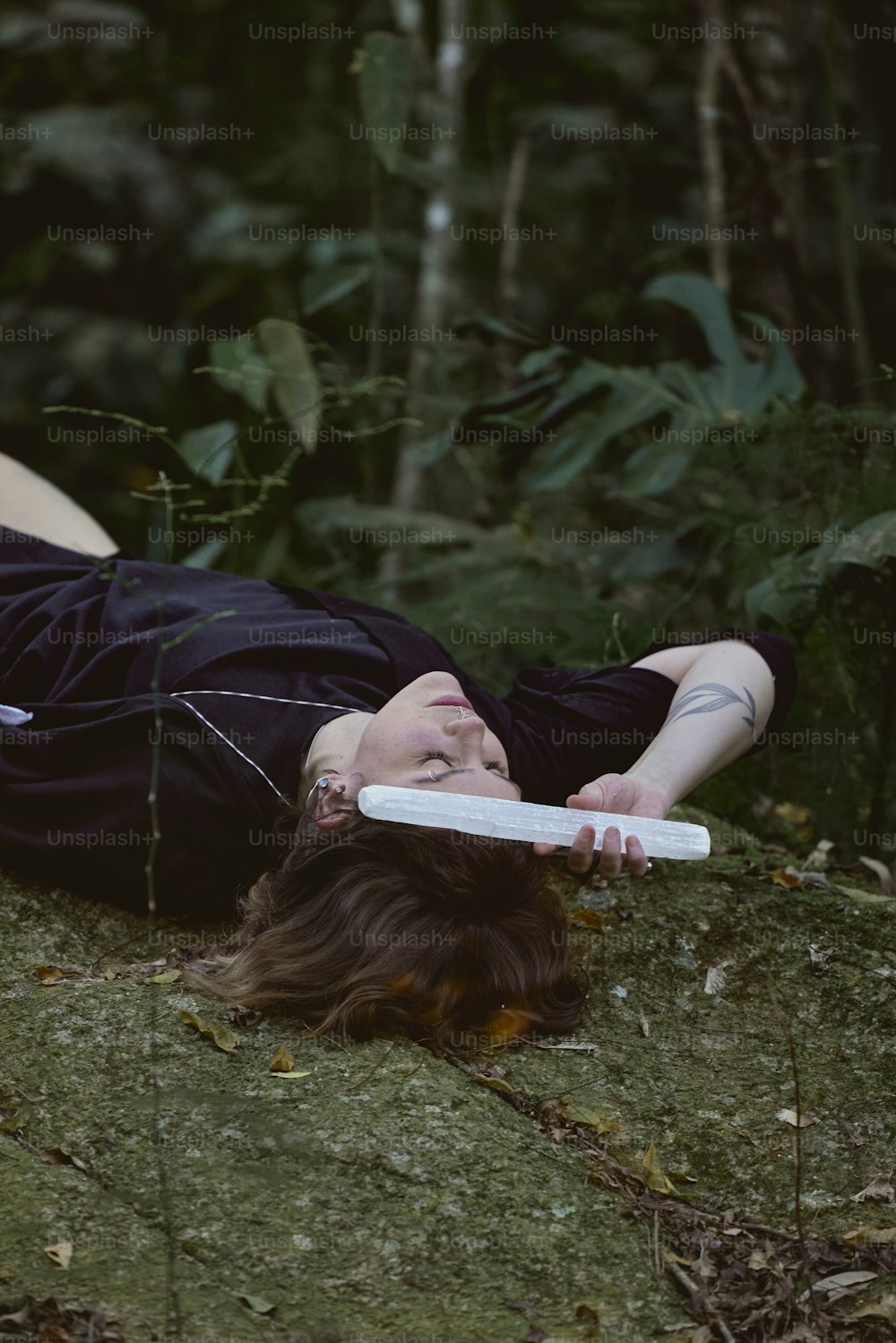 uma mulher deitada no chão com um frisbee na boca