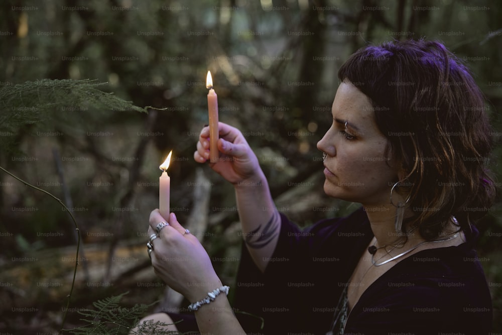 a woman holding a lit candle in a forest