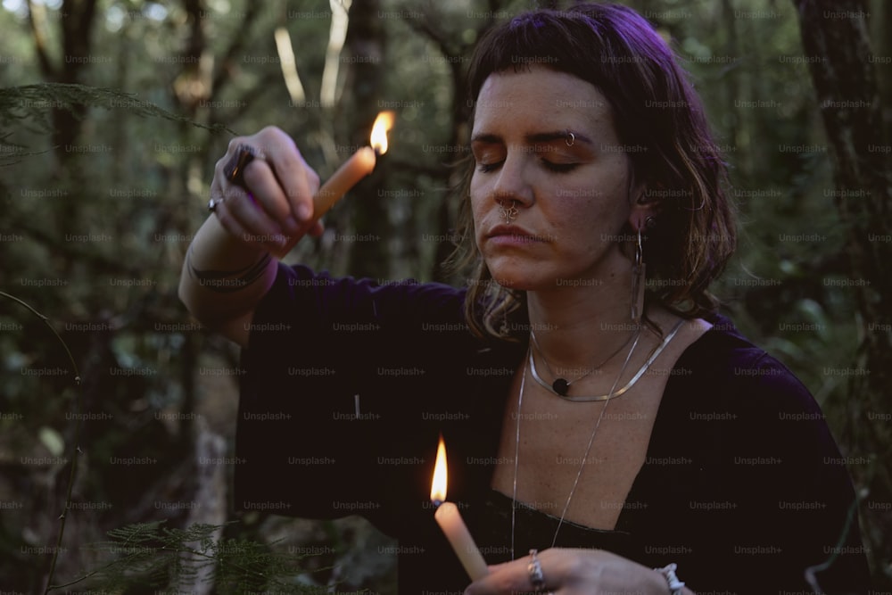 Una donna che accende una candela nel bosco