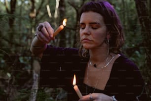 a woman lighting a candle in the woods
