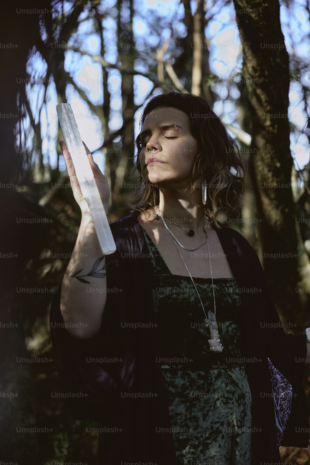 a woman standing in a forest holding a piece of paper