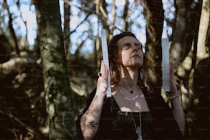 a woman standing in the woods holding a pair of scissors