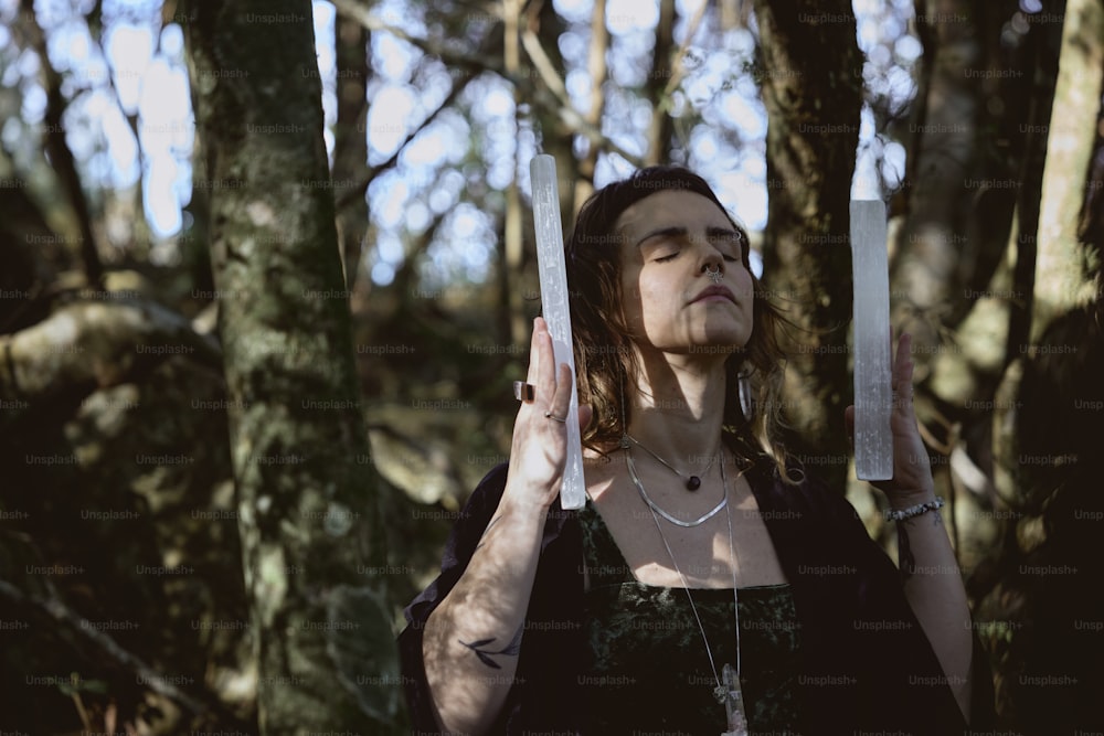 Une femme debout dans les bois tenant une paire de ciseaux