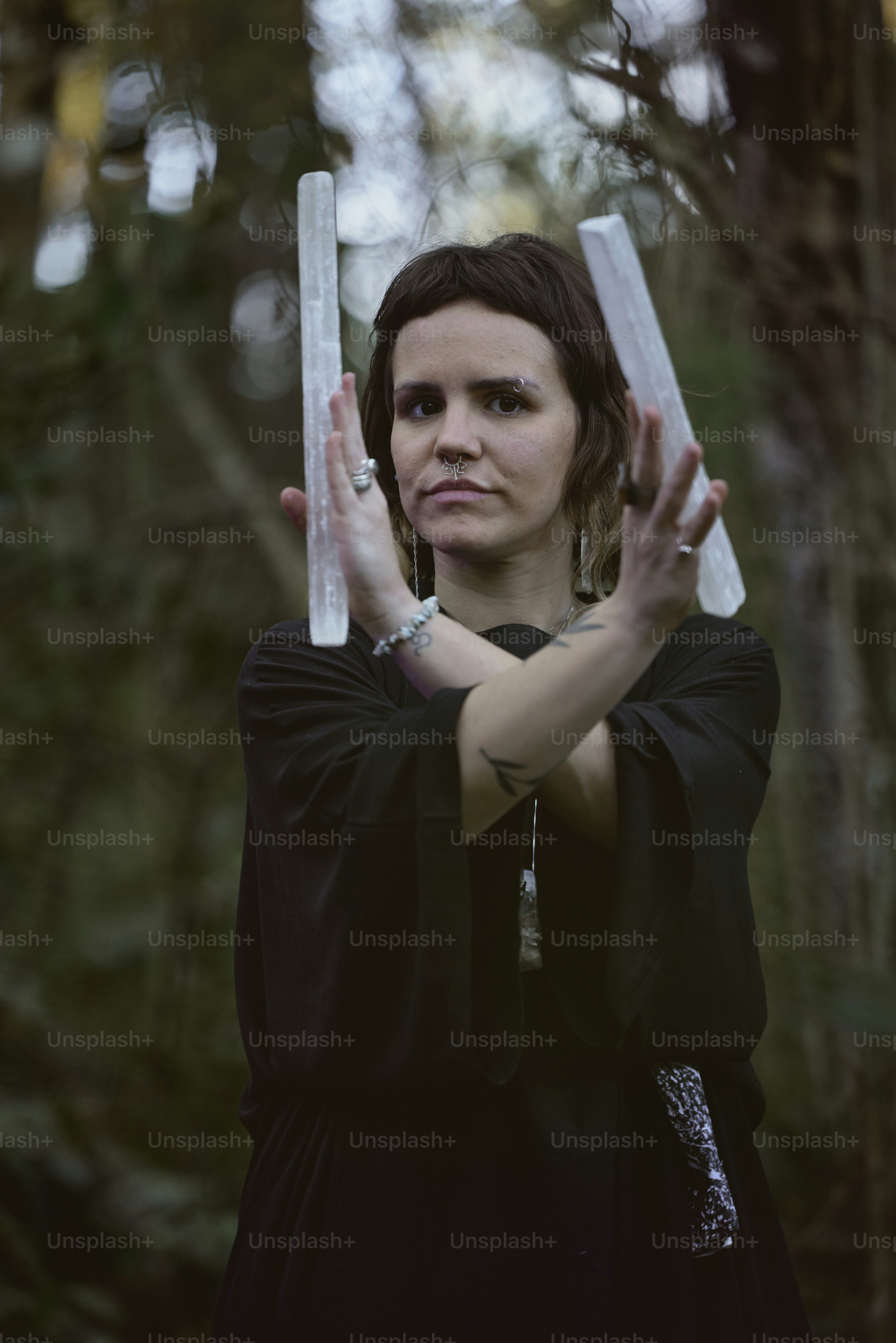 a woman in a black dress is holding two white sticks
