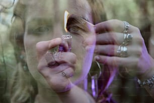 a woman holding a piece of jewelry in front of her face