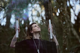 a woman in a black dress holding two white candles