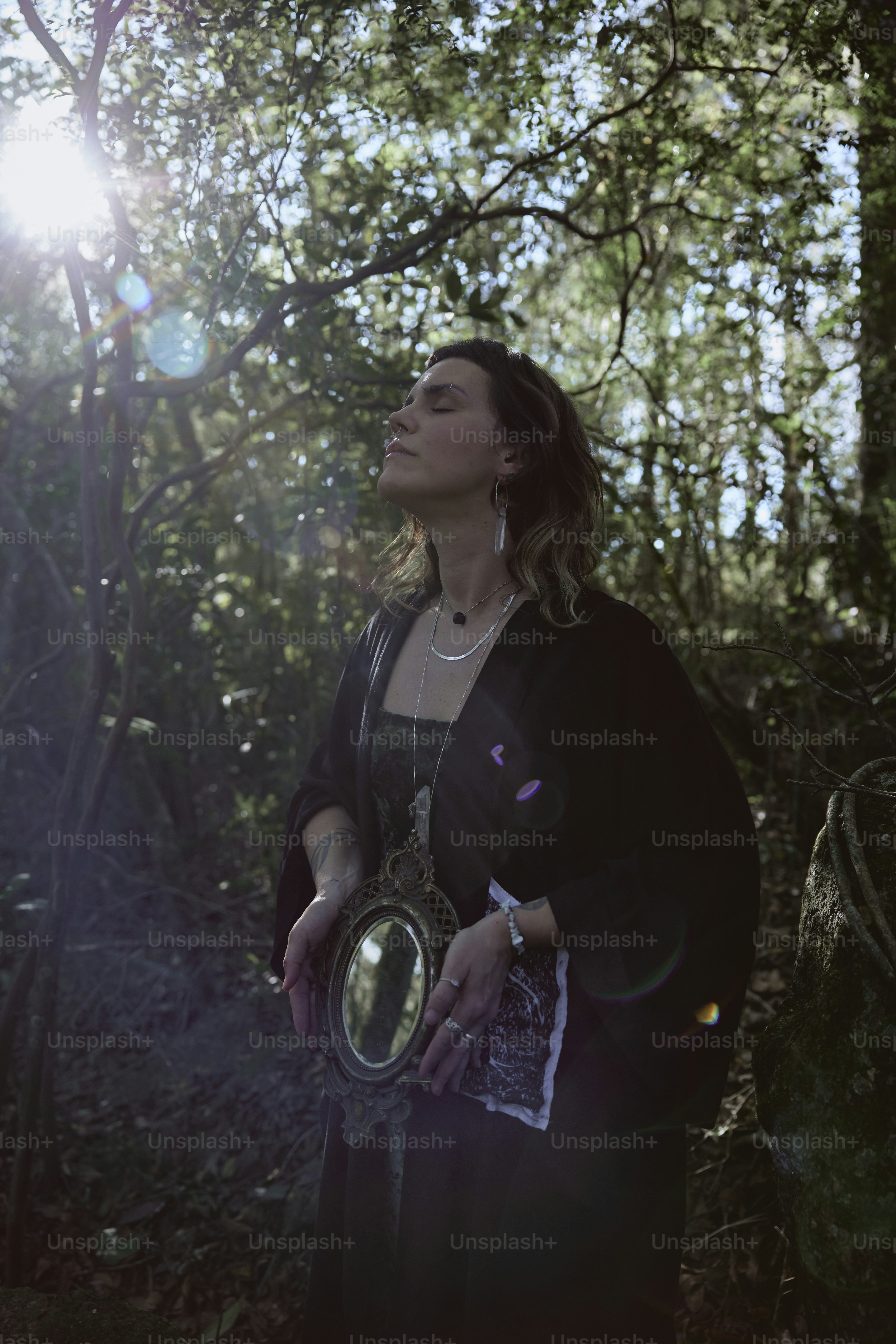 a woman standing in the woods holding a mirror