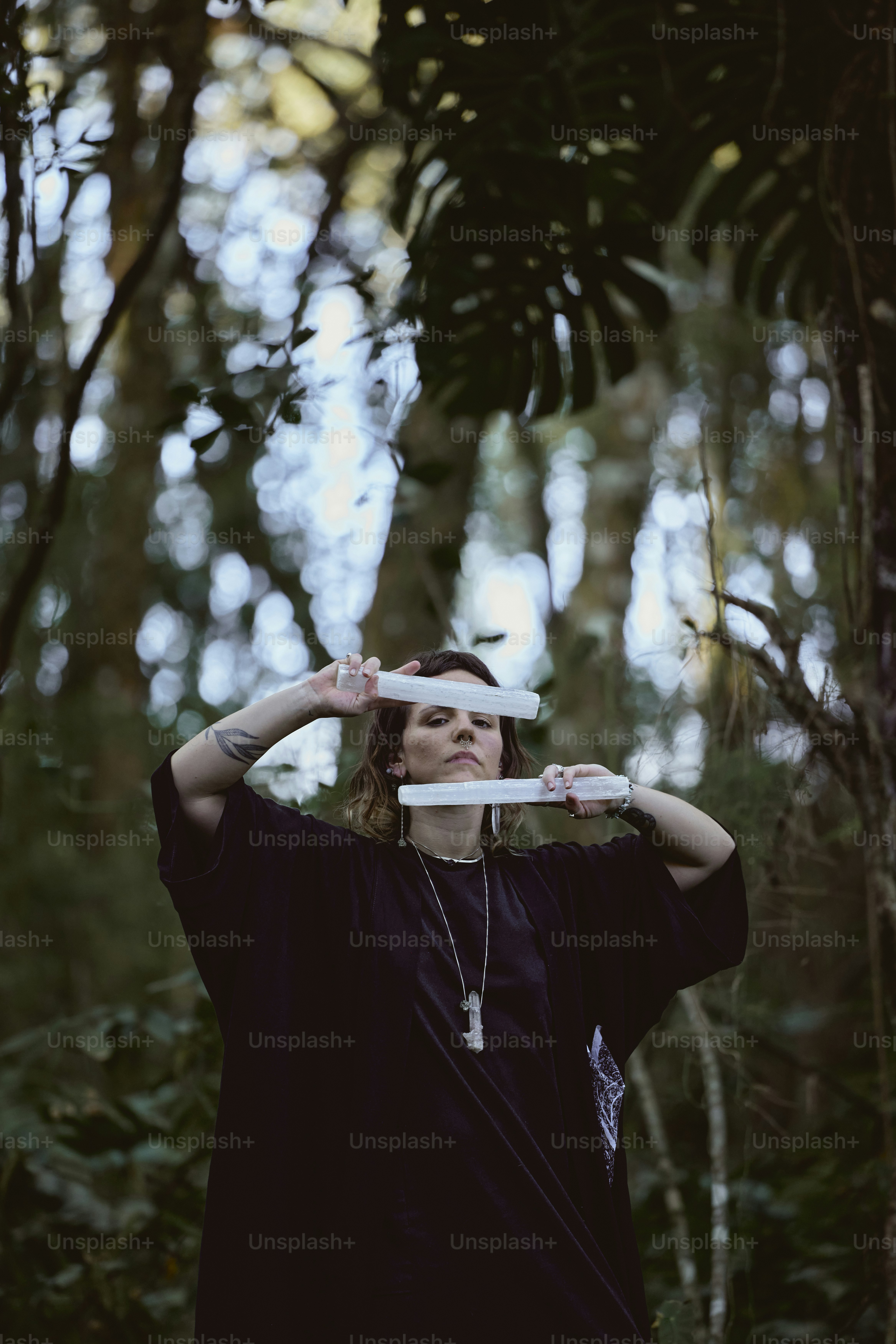 a woman standing in a forest holding a frisbee