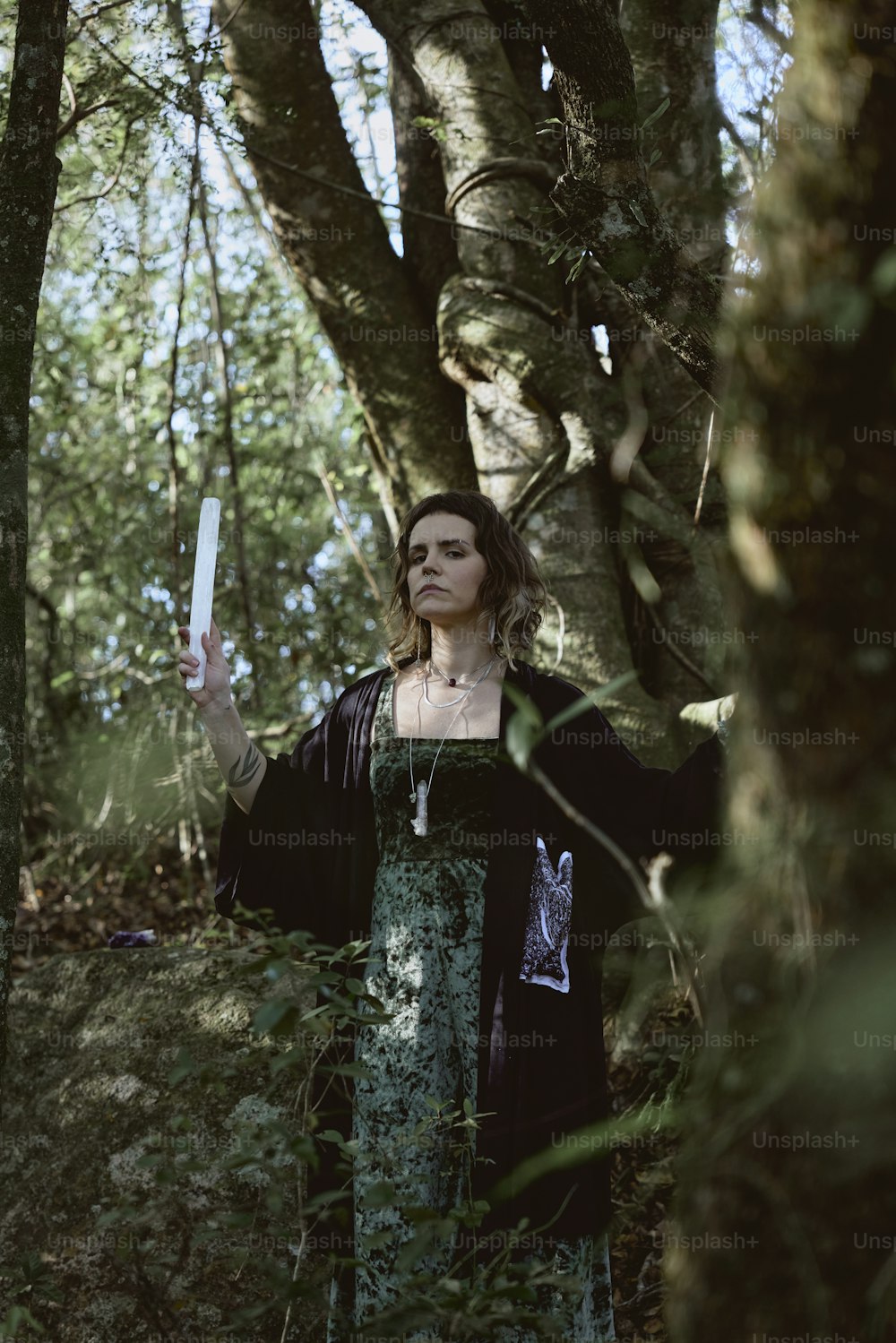 a woman standing in the woods holding a knife