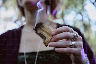 a woman holding a piece of wood with smoke coming out of it