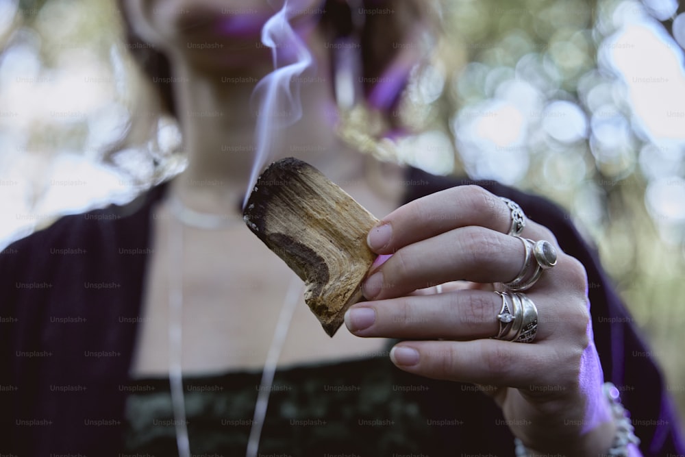 a woman holding a piece of wood with smoke coming out of it